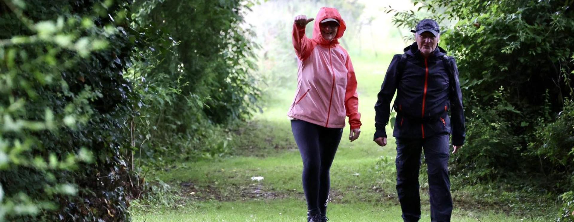 un homme et une femme marchant sur un chemin arboré