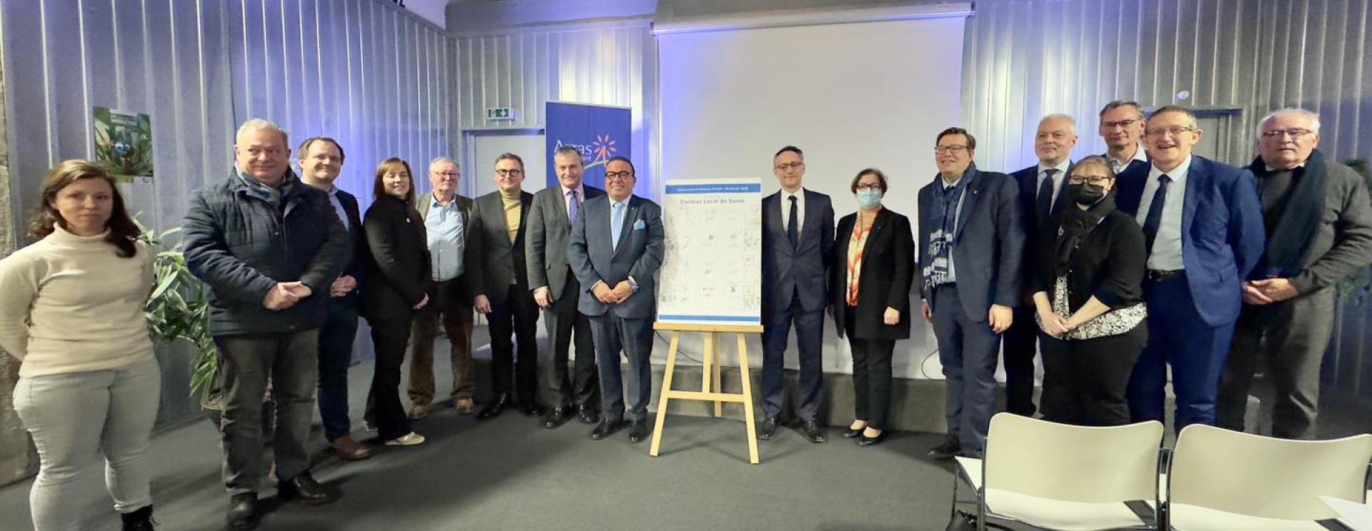 personnes autour d'un chevalet avec un panneau portant l'inscription contra local de santé